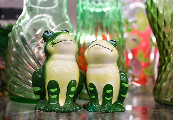 Two happy decorative frogs gaze upwards surrounded by green and pink glass