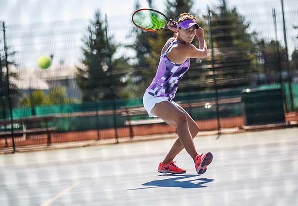 Female tennis player hits the ball